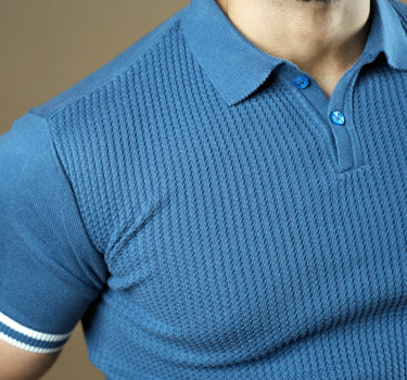 Textured knitted polo blue T-shirt with black trousers.